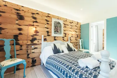 a bedroom with a bed and a wooden wall at Storm in a tea cup in St Ives