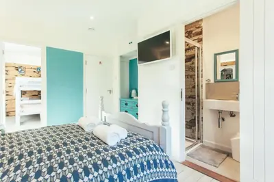 a white bedroom with a bed and a bathroom at Storm in a tea cup in St Ives