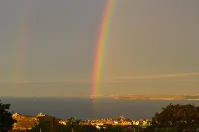 a rainbow over the water with a city at Storm in a tea cup in St Ives