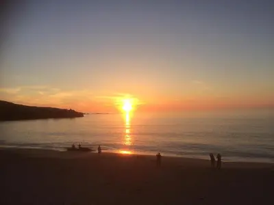 a group of people standing on the beach at sunset at Storm in a tea cup in St Ives
