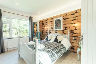 a bedroom with a white bed and wooden walls at Storm in a tea cup in St Ives