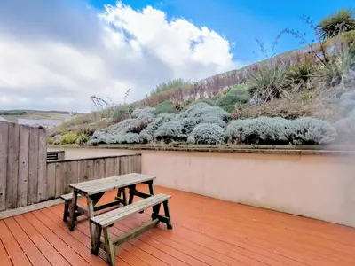 a wooden deck with a bench on top of it at Waves Apartments in Newquay