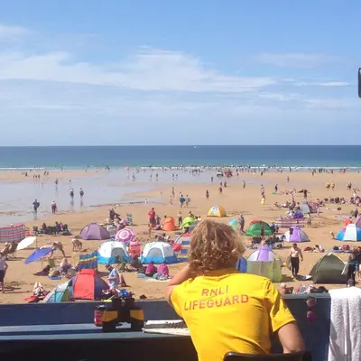a woman sitting in a chair at a beach at Waves Apartments in Newquay