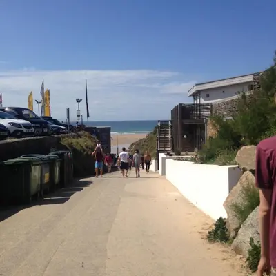 a group of people walking down a sidewalk near the beach at Waves Apartments in Newquay