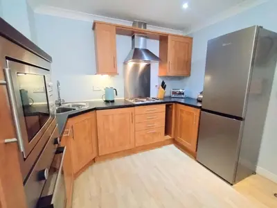 a kitchen with wooden cabinets and a stainless steel refrigerator at Waves Apartments in Newquay