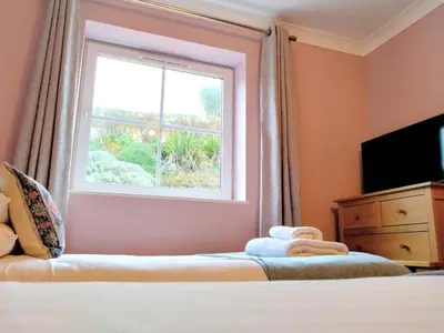 a bedroom with a window and a bed and a television at Waves Apartments in Newquay