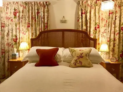a bedroom with a bed with pillows and curtains at Cyntwell Guest Accommodation in Padstow