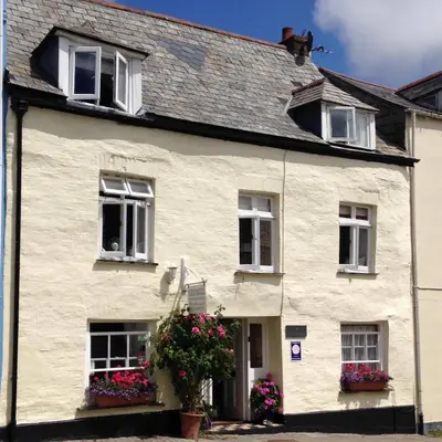 a white house with flowers in front of it at Cyntwell Guest Accommodation in Padstow