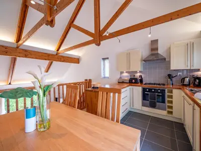 a kitchen with a wooden table and wooden beams at The Valley in Perranwell