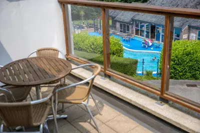 a patio with a table and chairs and a swimming pool at The Valley in Perranwell