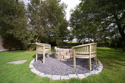 two benches sitting next to a fire pit in a park at Talehay Cottages in Looe