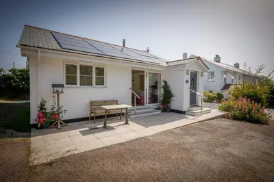 a white house with a bench on a patio at Treweens in Wadebridge