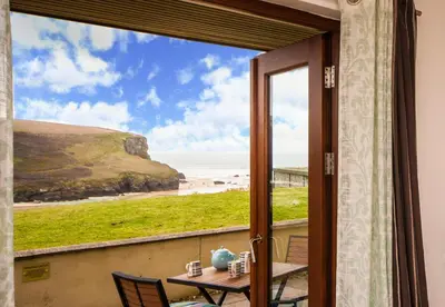 a view of the beach from the balcony of a house at White Lodge Apartments in Mawgan Porth