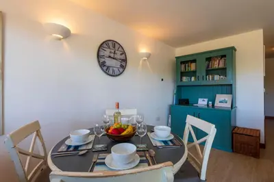 a dining room with a table with a clock on the wall at White Lodge Apartments in Mawgan Porth