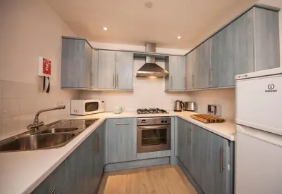 a kitchen with blue cabinets and a sink at White Lodge Apartments in Mawgan Porth