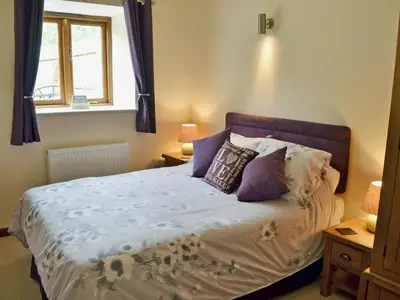 a bedroom with a bed with purple pillows and a window at Black Thorn Cottage in Falmouth