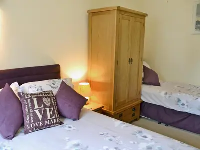 a bedroom with a bed and a wooden cabinet at Black Thorn Cottage in Falmouth