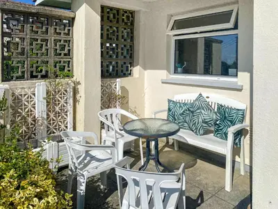 a patio with a table and chairs and a bench at Merriview in Germoe