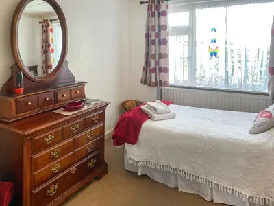 a bedroom with a bed and a dresser and a mirror at Merriview in Germoe
