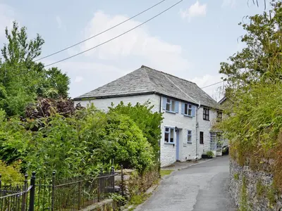 a white house with a gray roof on a street at Ostlers in Boscastle