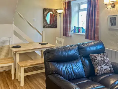 a living room with a leather couch and a table at Ostlers in Boscastle