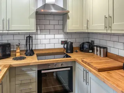 a kitchen with white cabinets and a stove top oven at Ostlers in Boscastle