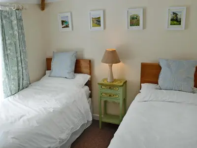 a bedroom with two beds and a lamp on a night stand at Ostlers in Boscastle