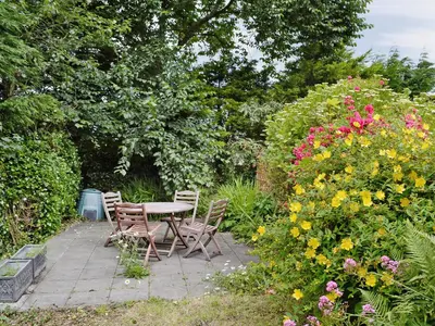 a patio with a table and chairs and flowers at Ostlers in Boscastle