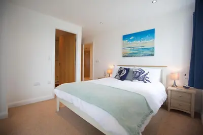 a bedroom with a large white bed with two lamps at Horizons Apartments Newquay in Newquay