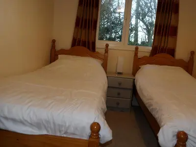 a bedroom with two beds and a dresser and two windows at Hengar Select in Saint Tudy