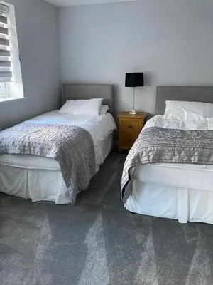 a bedroom with two beds and a table with a lamp at Shorthorn Apartment, 53a Sea Road in Carlyon Bay
