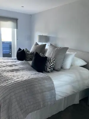 a large white bed with many pillows on it at Shorthorn Apartment, 53a Sea Road in Carlyon Bay