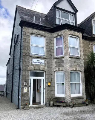 a brick house with a sign that reads the dumination at Donnington Guesthouse in Truro