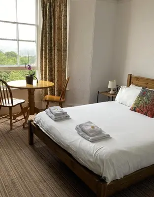 a bedroom with a bed and a table and a window at Donnington Guesthouse in Truro