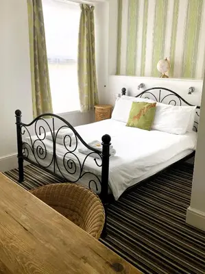 a bedroom with a bed with white sheets and a window at Donnington Guesthouse in Truro