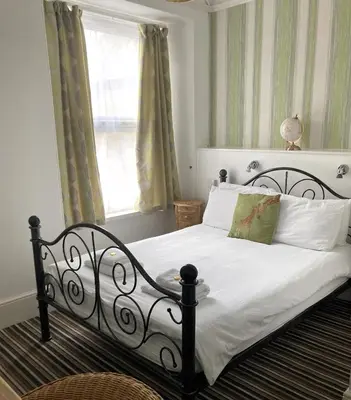 a bedroom with a bed with white sheets and a window at Donnington Guesthouse in Truro