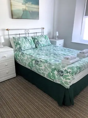 a bedroom with a bed with a green and white comforter at Donnington Guesthouse in Truro