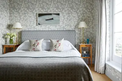a bedroom with a bed and two tables and a window at Hotel Tresanton in Saint Mawes