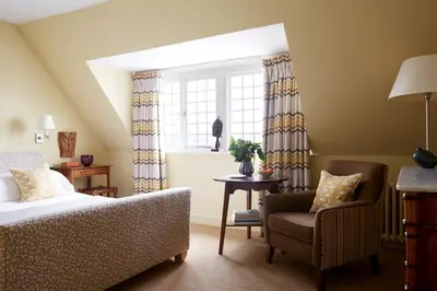 a bedroom with a bed and a chair and a window at Hotel Tresanton in Saint Mawes