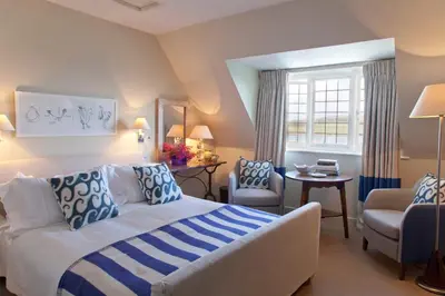 a bedroom with a bed and chairs and a window at Hotel Tresanton in Saint Mawes