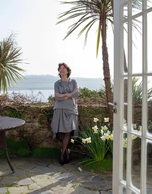a woman standing next to a wall with the ocean at Hotel Tresanton in Saint Mawes