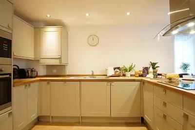 a kitchen with white cabinets and a clock on the wall at Ocean Views 4 in Newquay