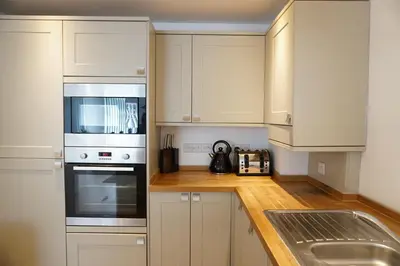 a kitchen with white cabinets and a stove and a sink at Ocean Views 4 in Newquay