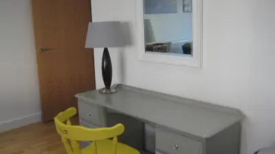 a desk with a lamp and a yellow chair in a room at SeaQuest 1 in Newquay