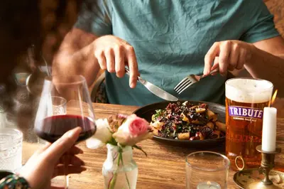 a person eating a plate of food with a glass of beer at Havener's in Fowey