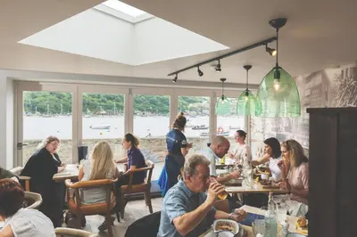 a group of people sitting at tables in a restaurant at Havener's in Fowey