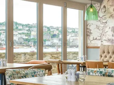 a restaurant with tables and chairs and a view of the water at Havener's in Fowey