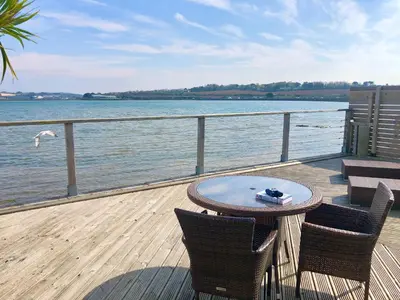 a table and chairs on a deck next to the water at The Old Quay House in Hayle