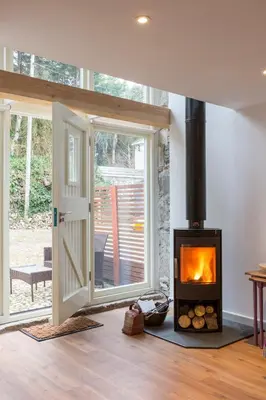 a living room with a wood stove in a room at Red River Stables - Peaceful, beautiful grounds, swimming pool, central location for West Cornwall in Camborne
