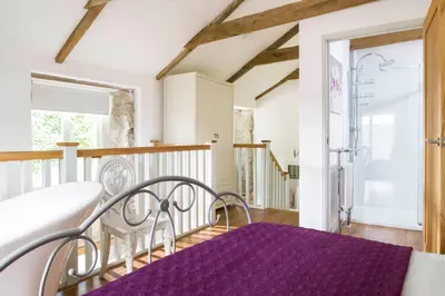 a bedroom with a bed and a purple rug at Red River Stables - Peaceful, beautiful grounds, swimming pool, central location for West Cornwall in Camborne